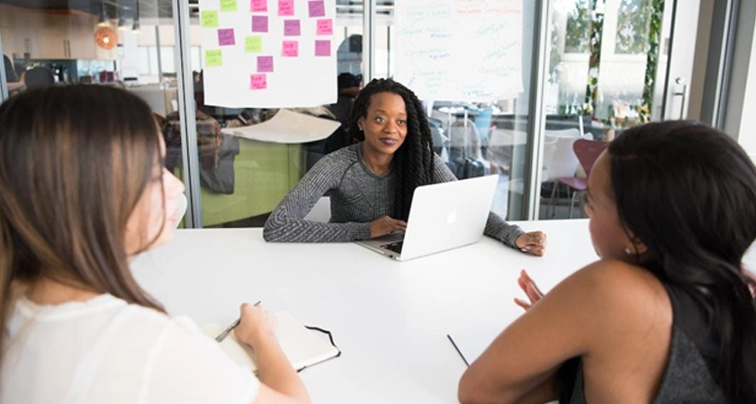 A three-person team sitting at a table discussing the benefits of professional services automation.